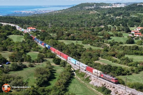 With the magnificent Trieste as a background, top 'n tail 363.033 + 363.015 lead a heavy container train out of Koper, passing the station of Crnotice